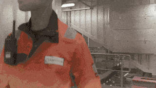A man in an orange jacket, identified as Biffa, is standing in a room.