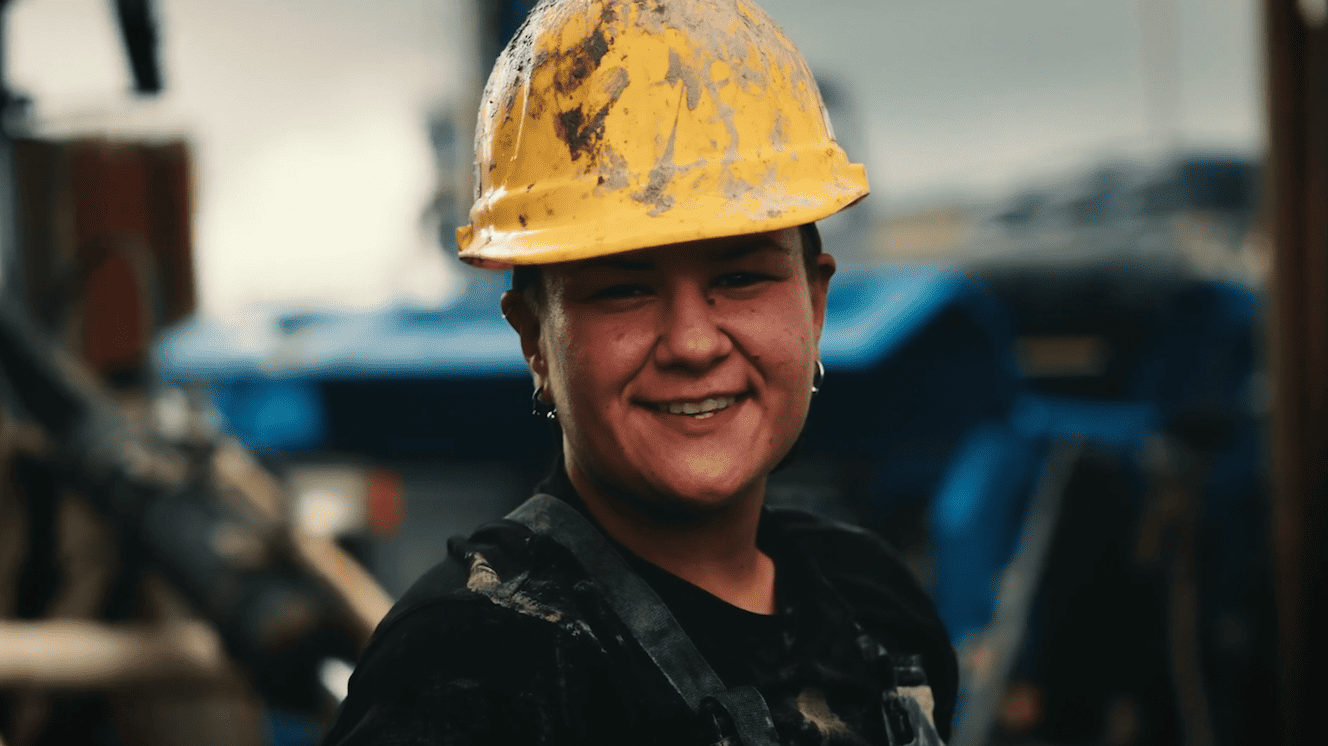 A woman wearing a hard hat and smiling while working at Geosource Energy.