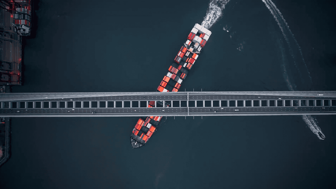 An aerial view of a container ship crossing a bridge operated by Amey PLC.